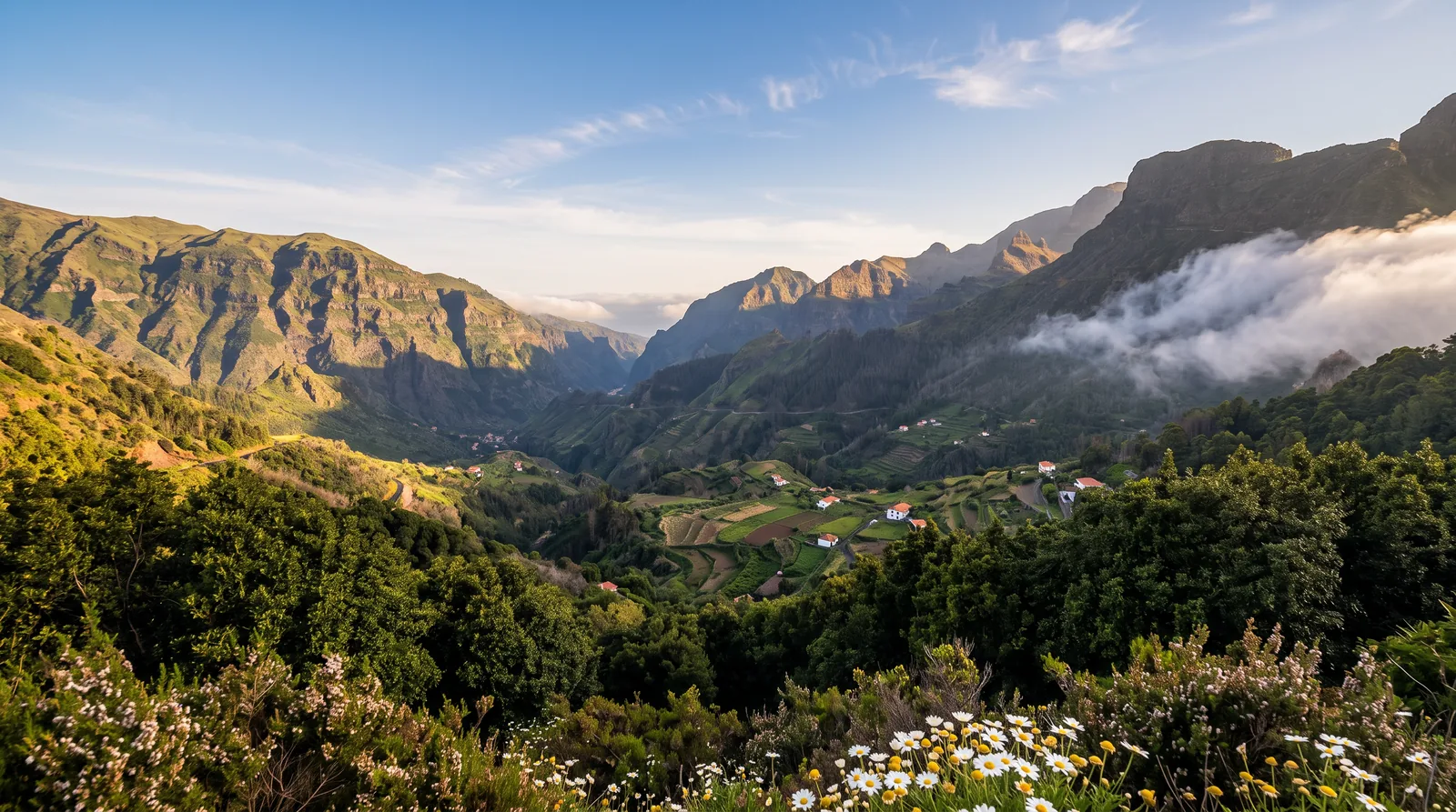 A deep green valley seen from a mountain pass, with cloud spilling over the ridge
