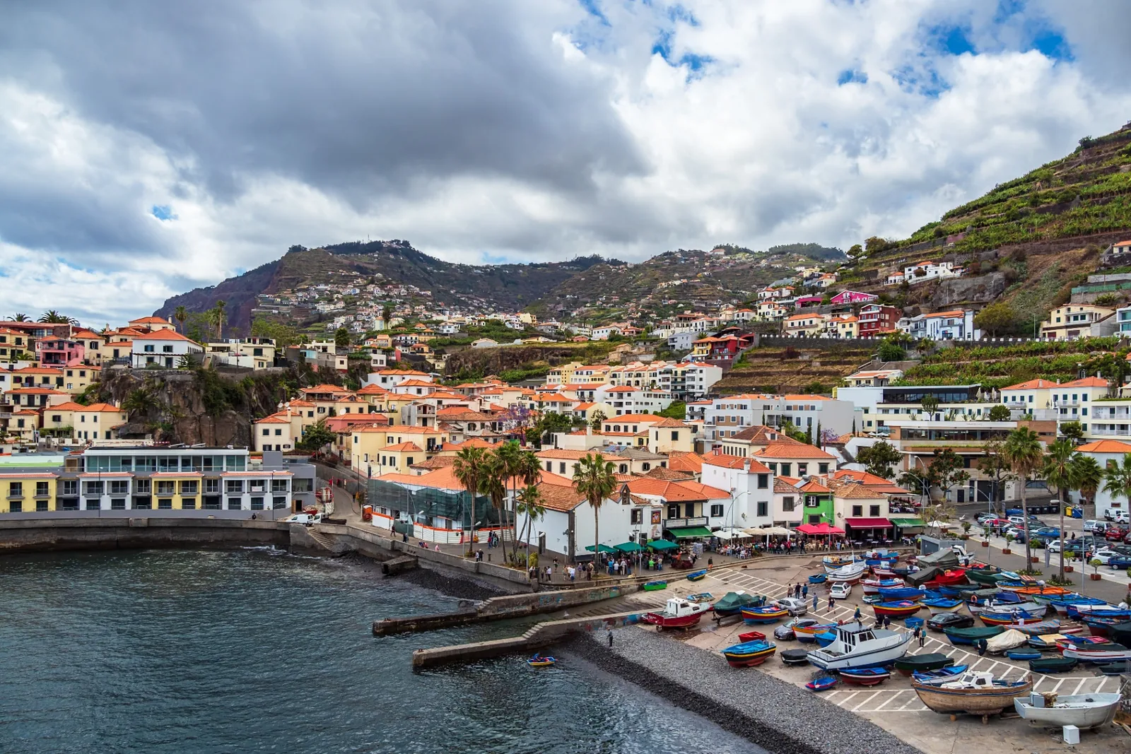 Painted fishing boats on the pebble beach of Câmara de Lobos with the village behind