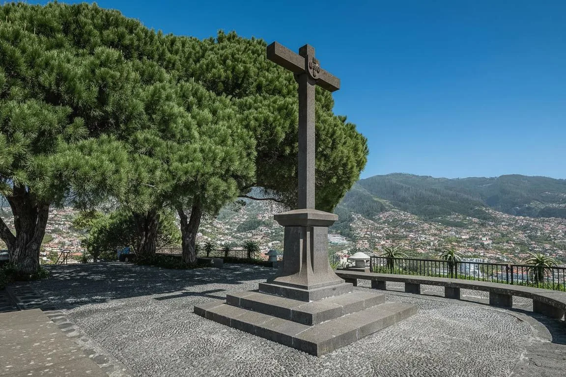 A stone cross on a paved terrace with Funchal spreading across the hillside behind