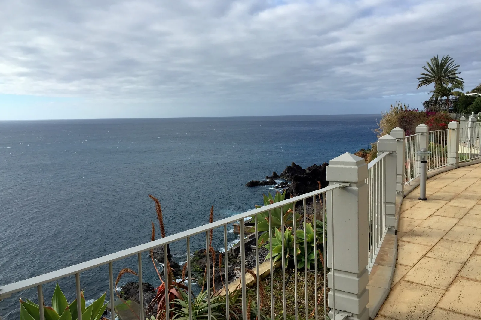 A railed section of the promenade above the ocean heading west
