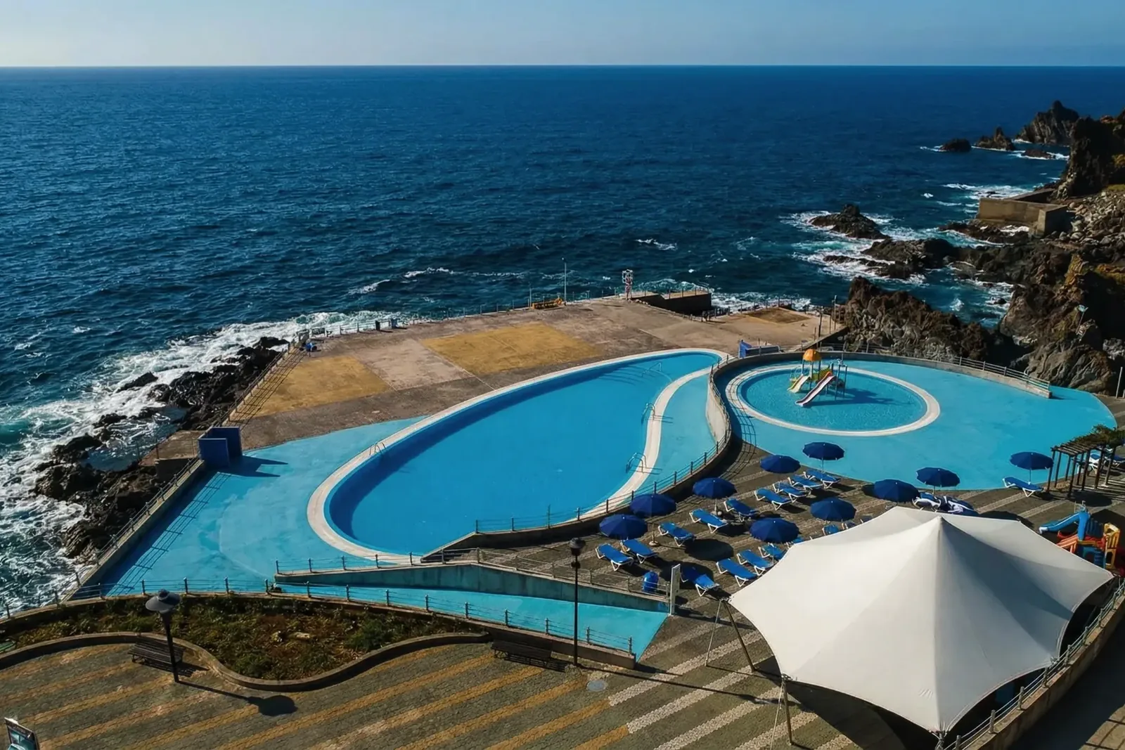 The kidney-shaped pool and children's pool of the Ponta Gorda complex above the lava rocks