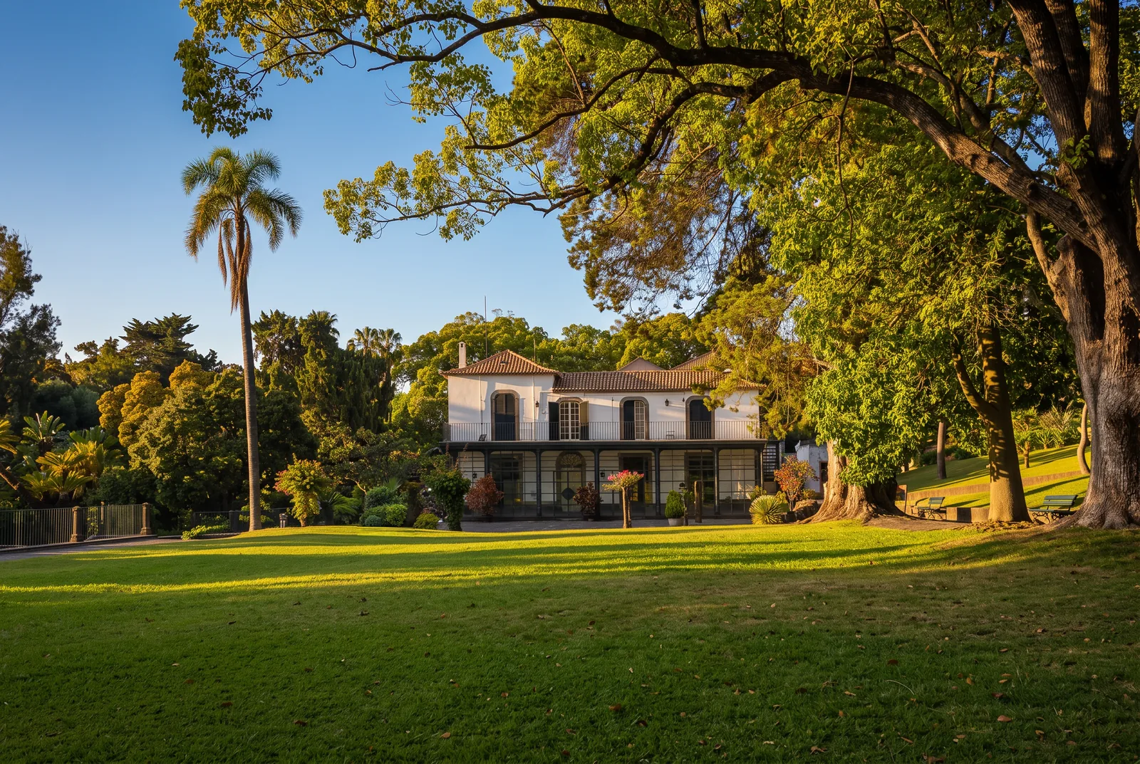 The white quinta house of Quinta Magnólia park behind an open lawn and mature trees