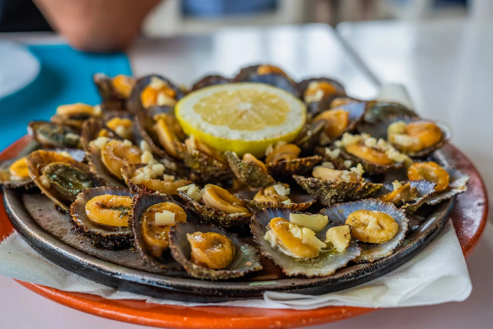 A plate of limpets grilled in their shells with garlic butter and a wedge of lemon