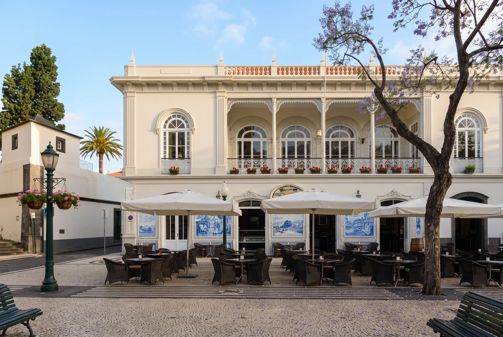 A historic café on Avenida Arriaga with blue and white azulejo panels and an empty terrace at first light