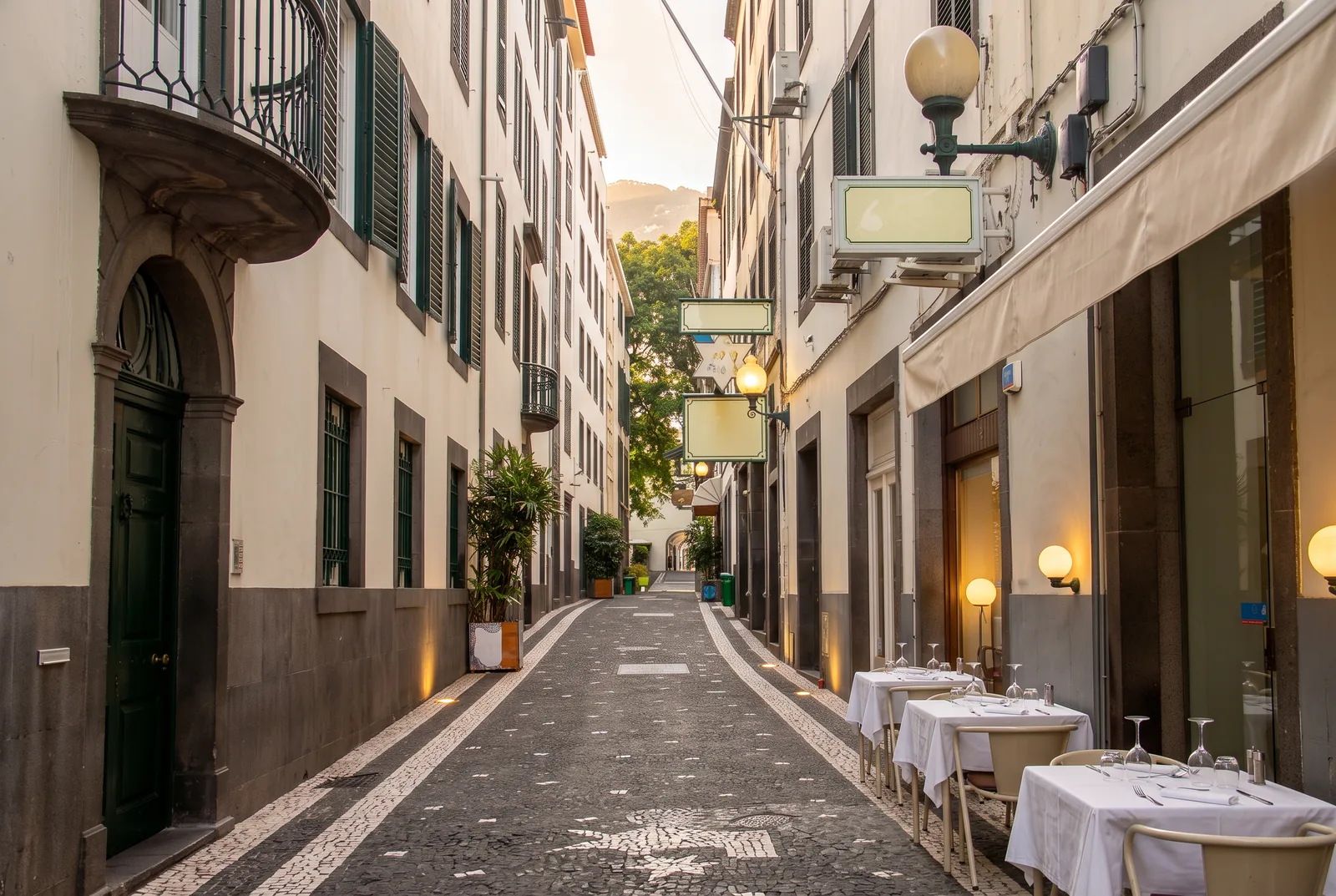 Rua da Alfândega in Funchal at dusk, with restaurant tables set out along the calçada