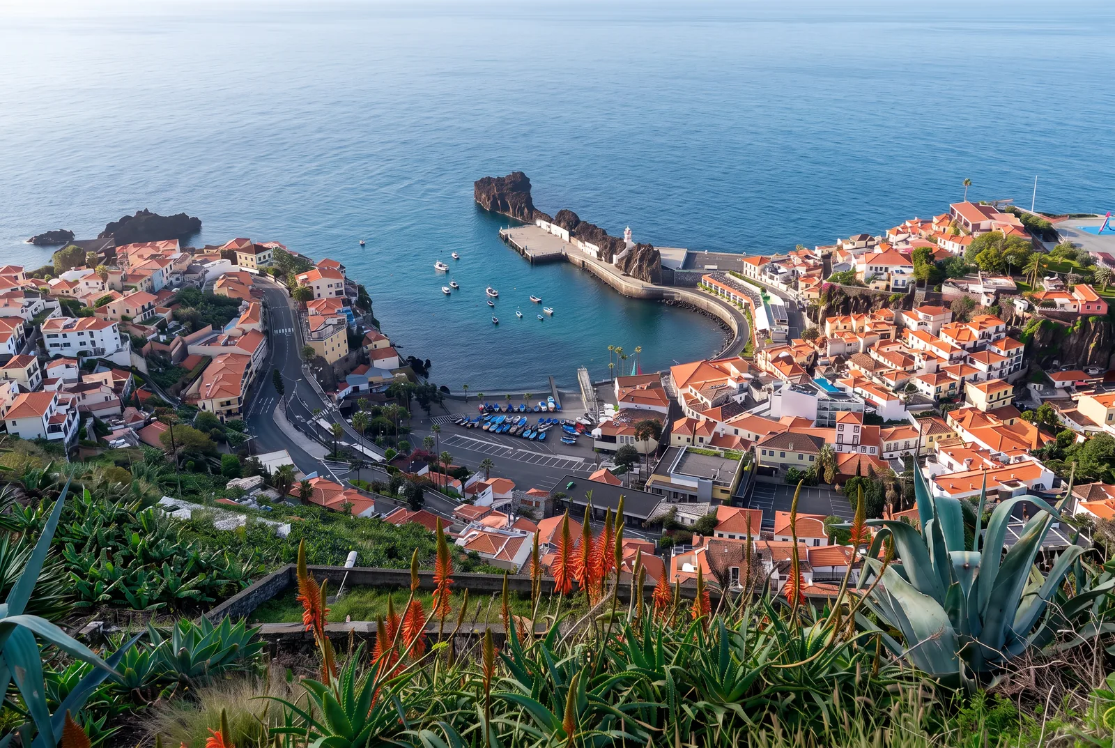 The bay of Câmara de Lobos at golden hour, with painted fishing boats hauled up on the shingle beach