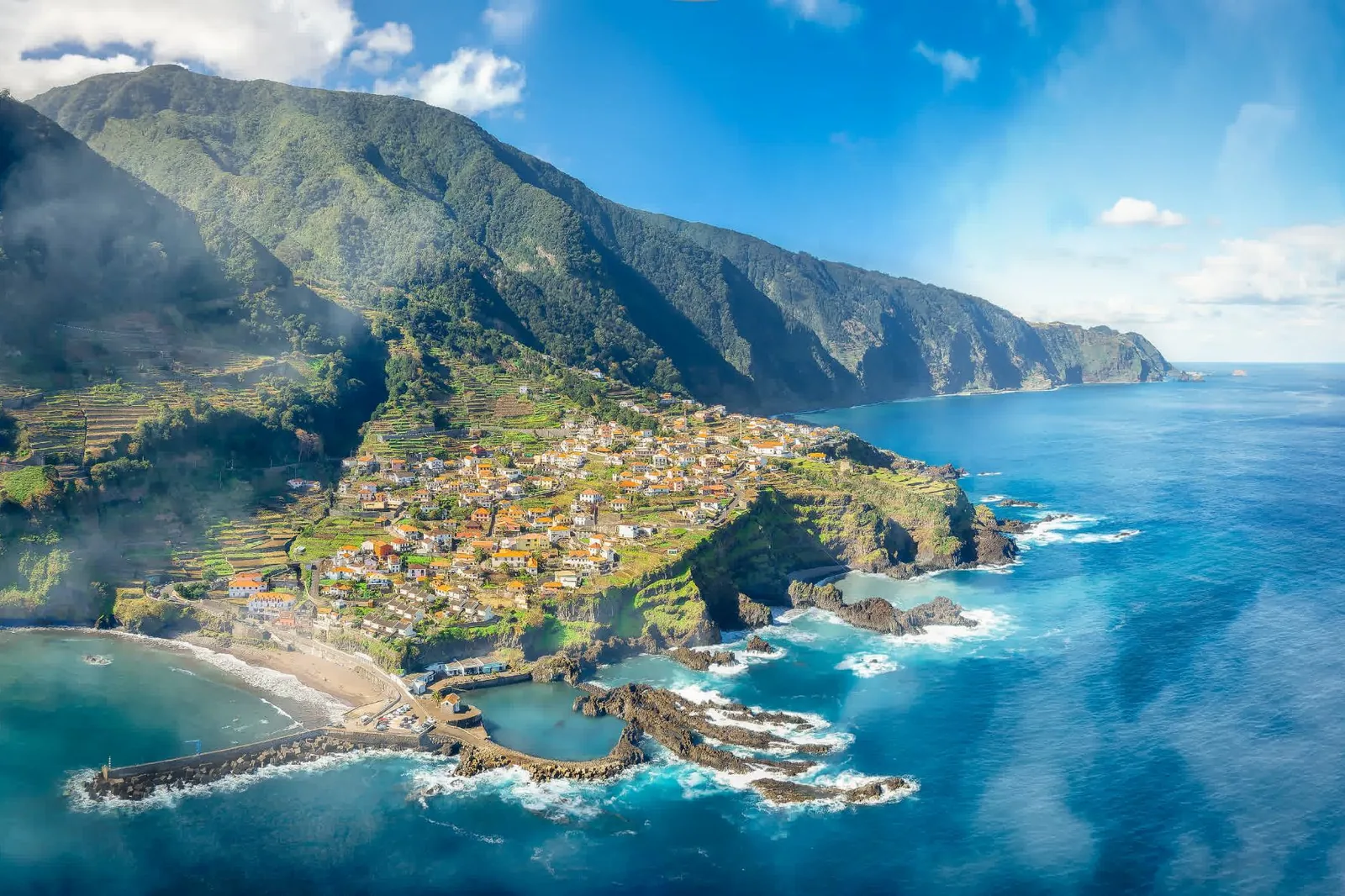 The north coast of Madeira with cloud caught on the ridge above a village and a rocky shore