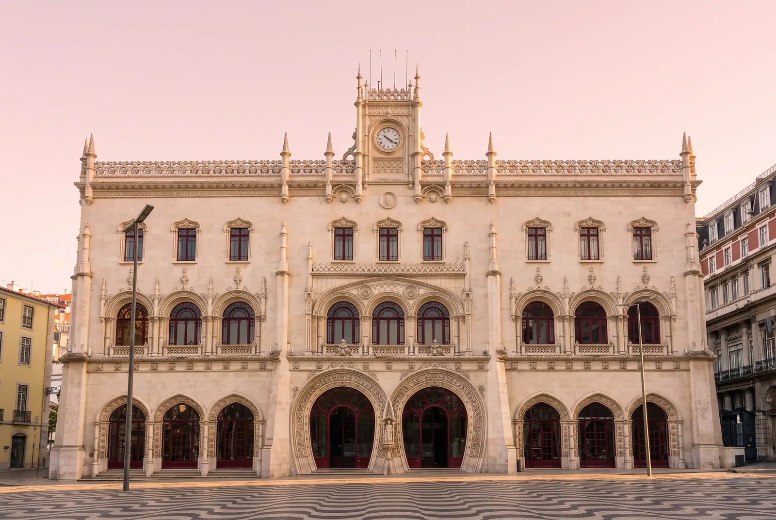 The Neo-Manueline facade of Rossio station in Lisbon at sunrise, with its two intertwined horseshoe arches