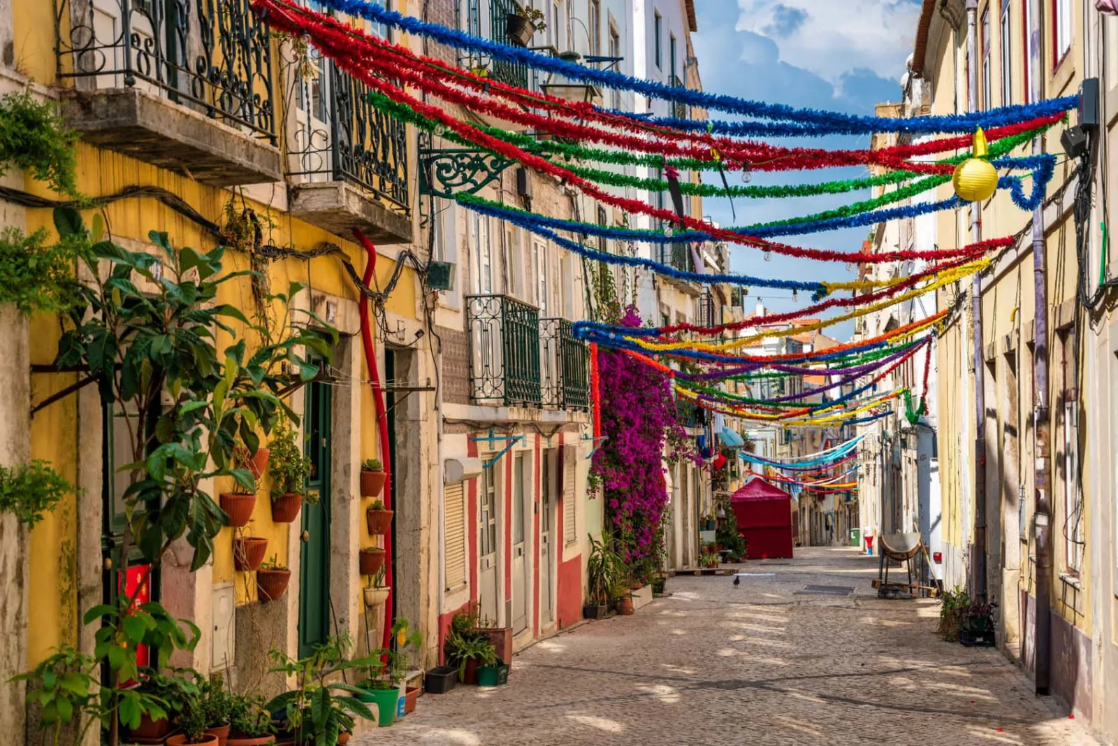 A narrow Alfama lane hung with festoon flags, painted facades on both sides