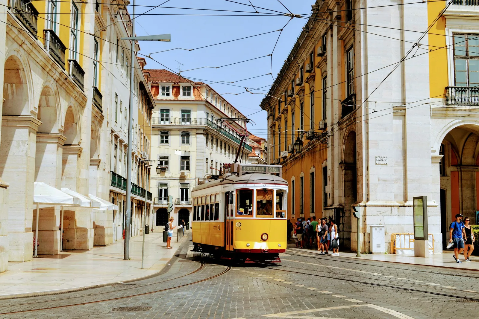 A yellow tram passing the arcaded buildings of central Lisbon