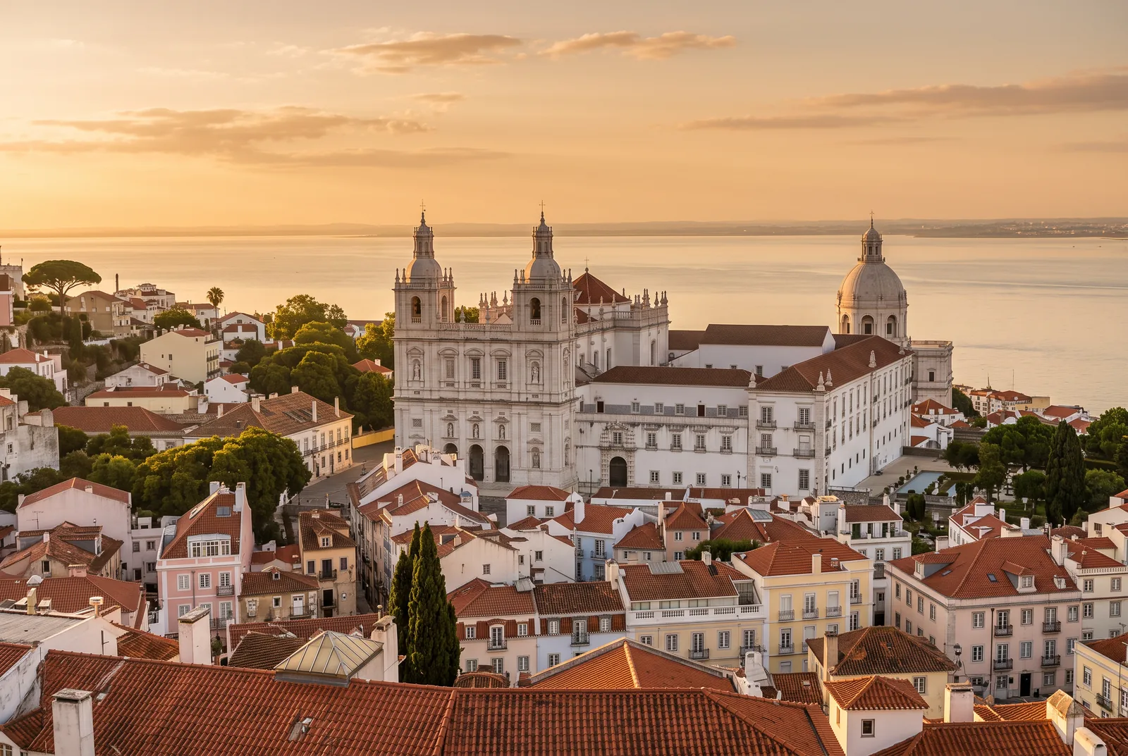 The rooftops of Graça and Alfama at golden hour with São Vicente de Fora and the Panteão Nacional